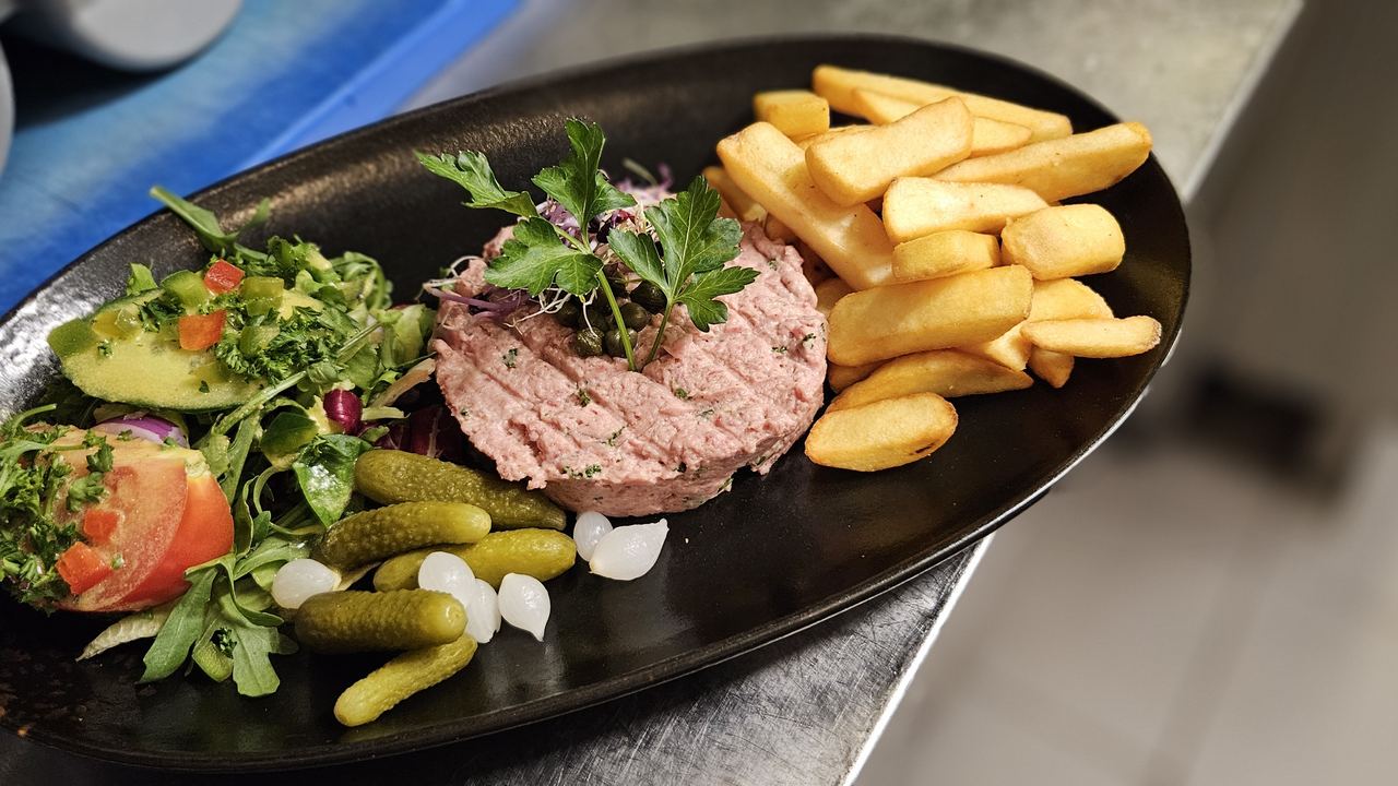Tartare de bœuf préparé maison, servi avec frites, pickles et salade